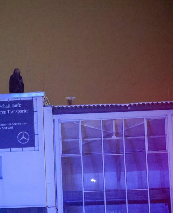 Eine Person harrt im Dunkeln auf einem Gebäudedach aus.