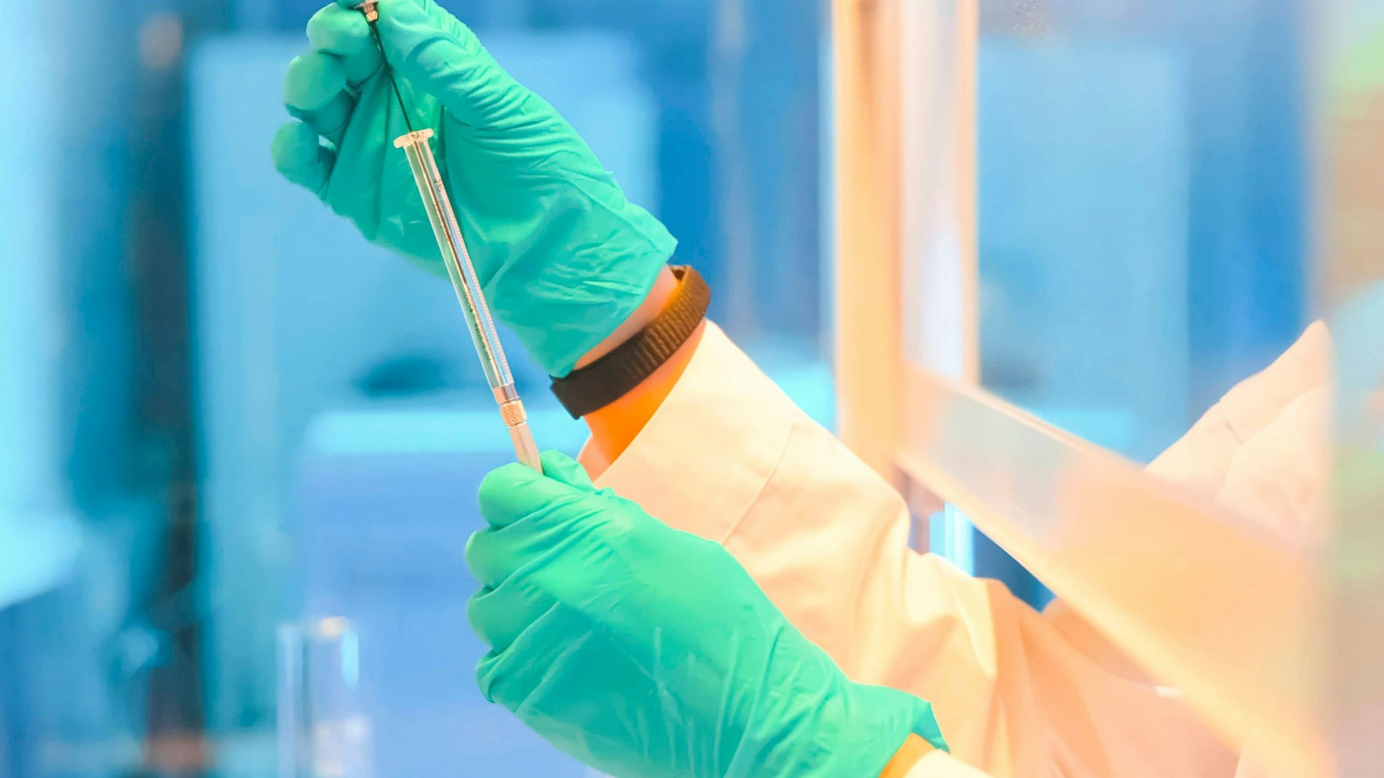 Laborant mit Handschuhen hält Spritze in Forschungseinrichtung