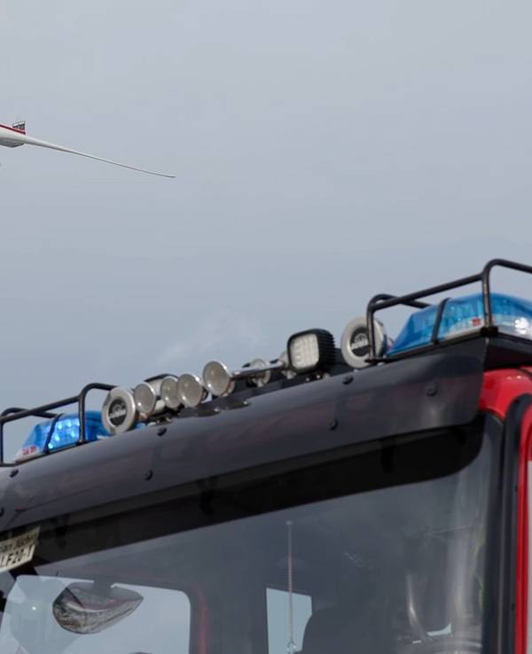 Ein Fahrzeug der Feuerwehr steht vor einem Windrad.