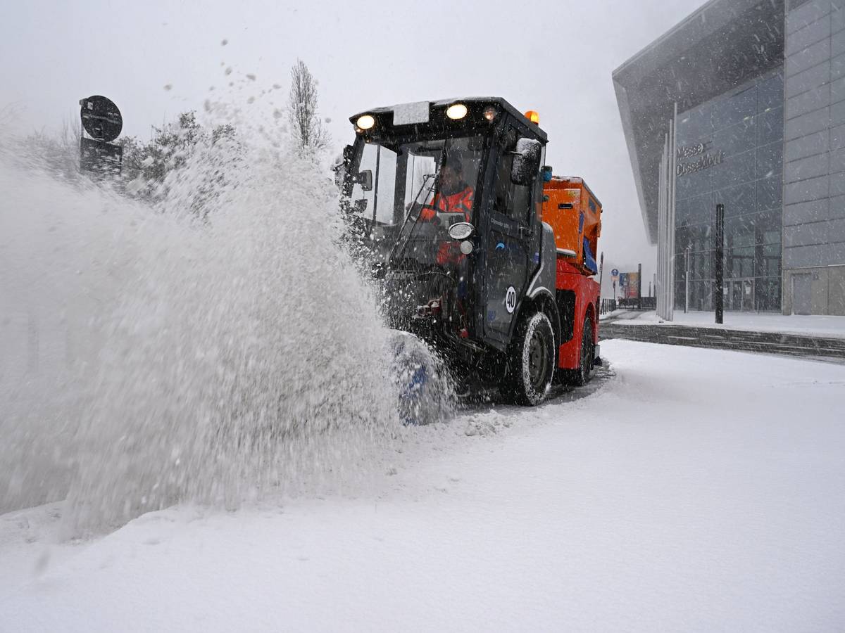Ein Räumfahrzeug beseitigt bei dichtem Schneetreiben mit einer Bürste Schnee von einer Straße bei der Düsseldorfer Messe
