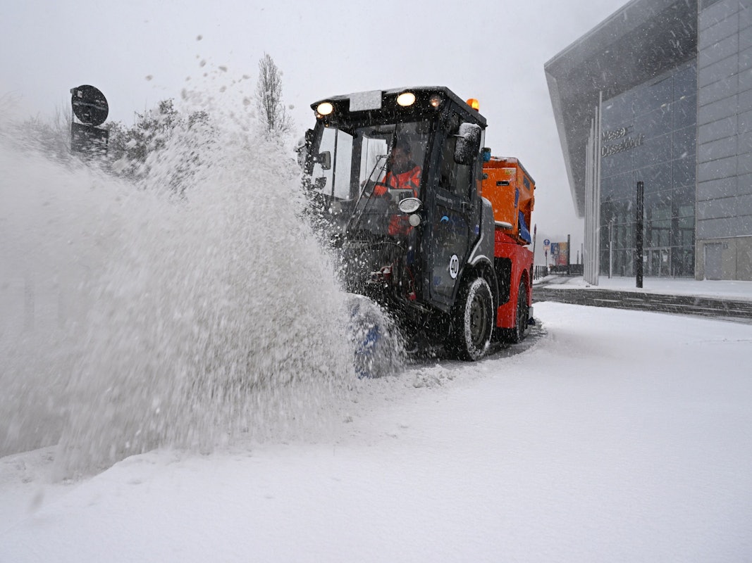 Ein Räumfahrzeug beseitigt bei dichtem Schneetreiben mit einer Bürste Schnee von einer Straße bei der Düsseldorfer Messe