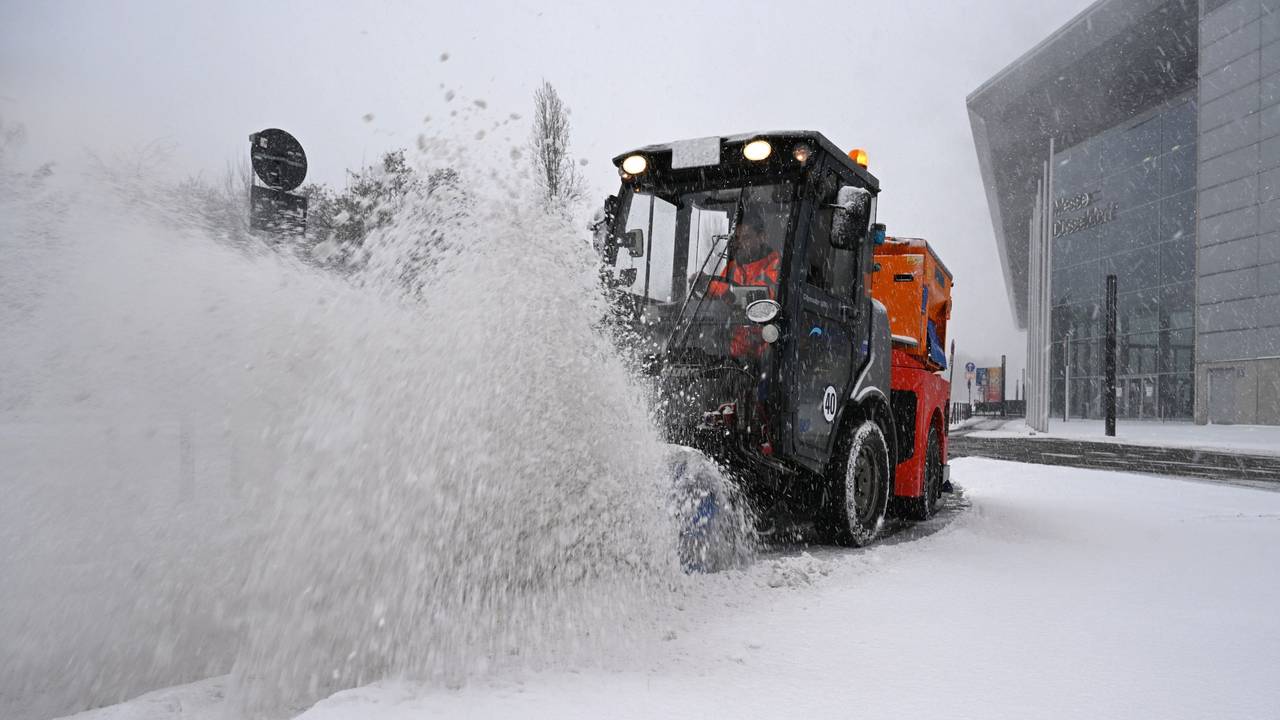 Ein Räumfahrzeug beseitigt bei dichtem Schneetreiben mit einer Bürste Schnee von einer Straße bei der Düsseldorfer Messe