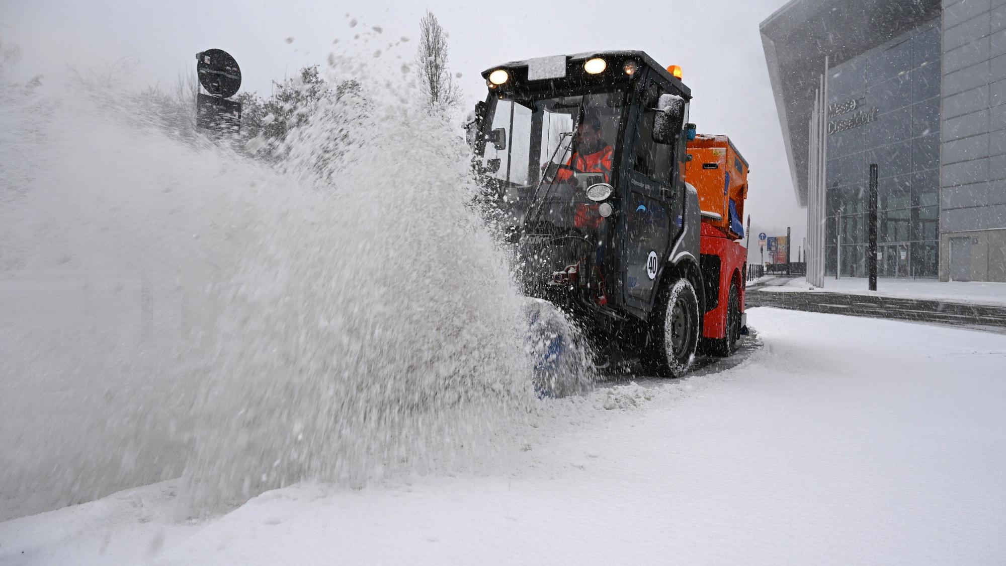 Ein Räumfahrzeug beseitigt bei dichtem Schneetreiben mit einer Bürste Schnee von einer Straße bei der Düsseldorfer Messe