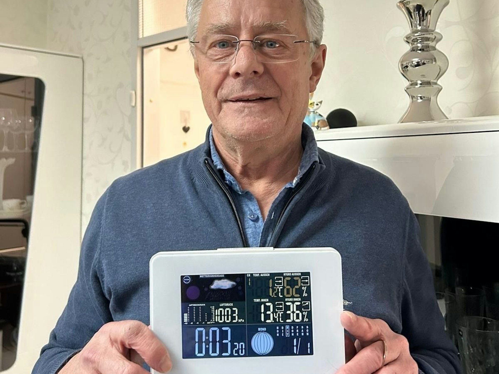 Ein Mann hält ein Thermometer vor sich.