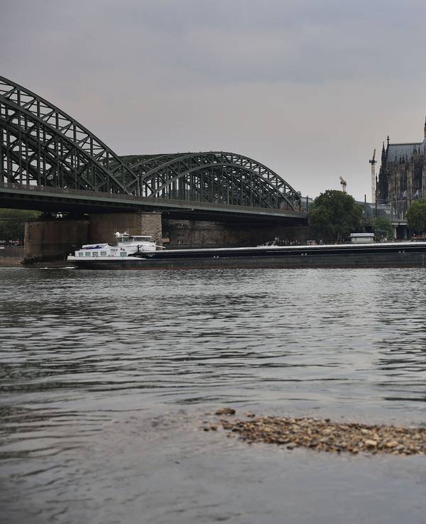 Ein Schiff fährt bei Niedrigwasser über den Rhein unter der Hohenzollernbrücke am Kölner Dom vorbei.