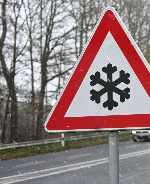 Ein Verkehrszeichen an einer Straße weist auf mögliche Glätte auf der Fahrbahn hin.