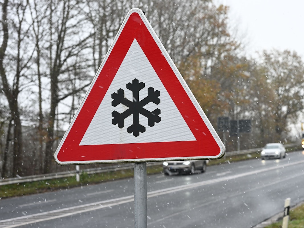 Ein Verkehrszeichen an einer Straße weist auf mögliche Glätte auf der Fahrbahn hin.