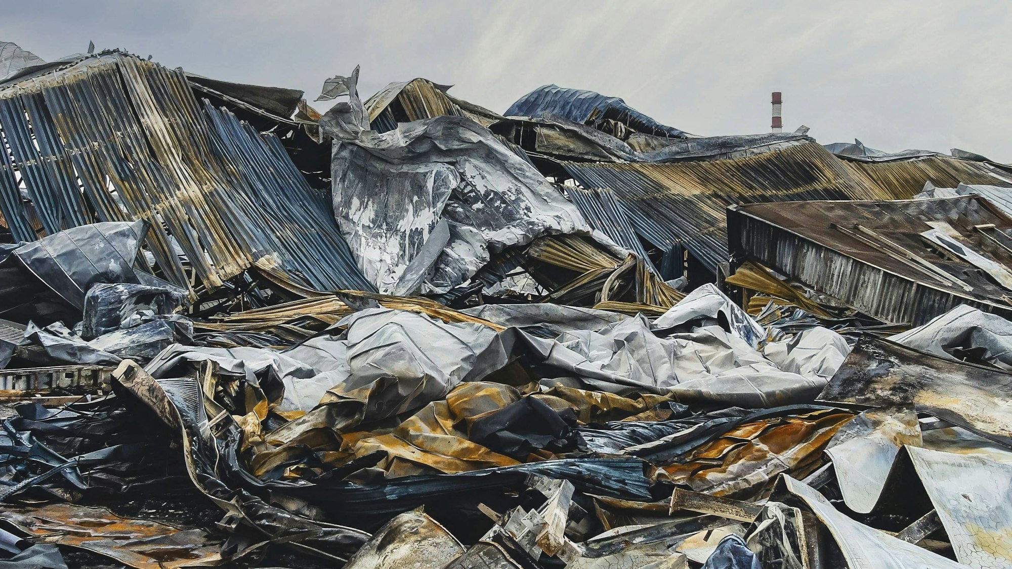 Trümmer eines abgebrannten Gebäudes unter bedecktem Himmel