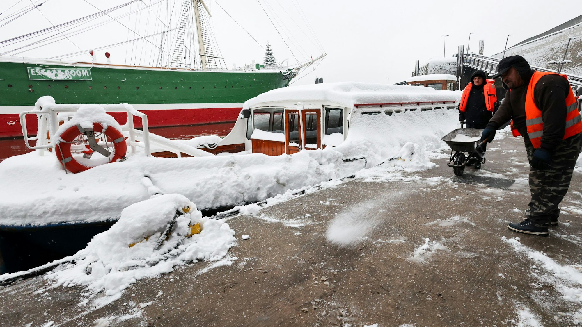 Mitarbeiter eines Betriebs für Schnee- und Eisbeseitigung streuen Salz auf dem Hafentor-Senatsponton an den Landungsbrücken im Hafen.