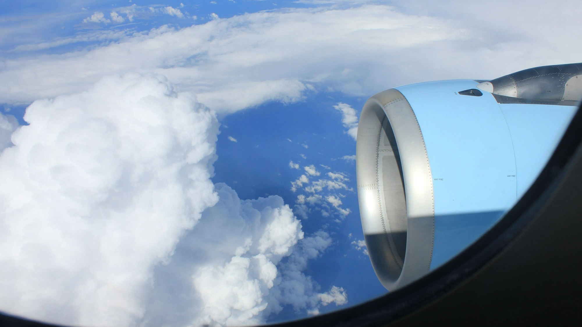 Wolken und Flugzeugtriebwerk bei blauem Himmel
