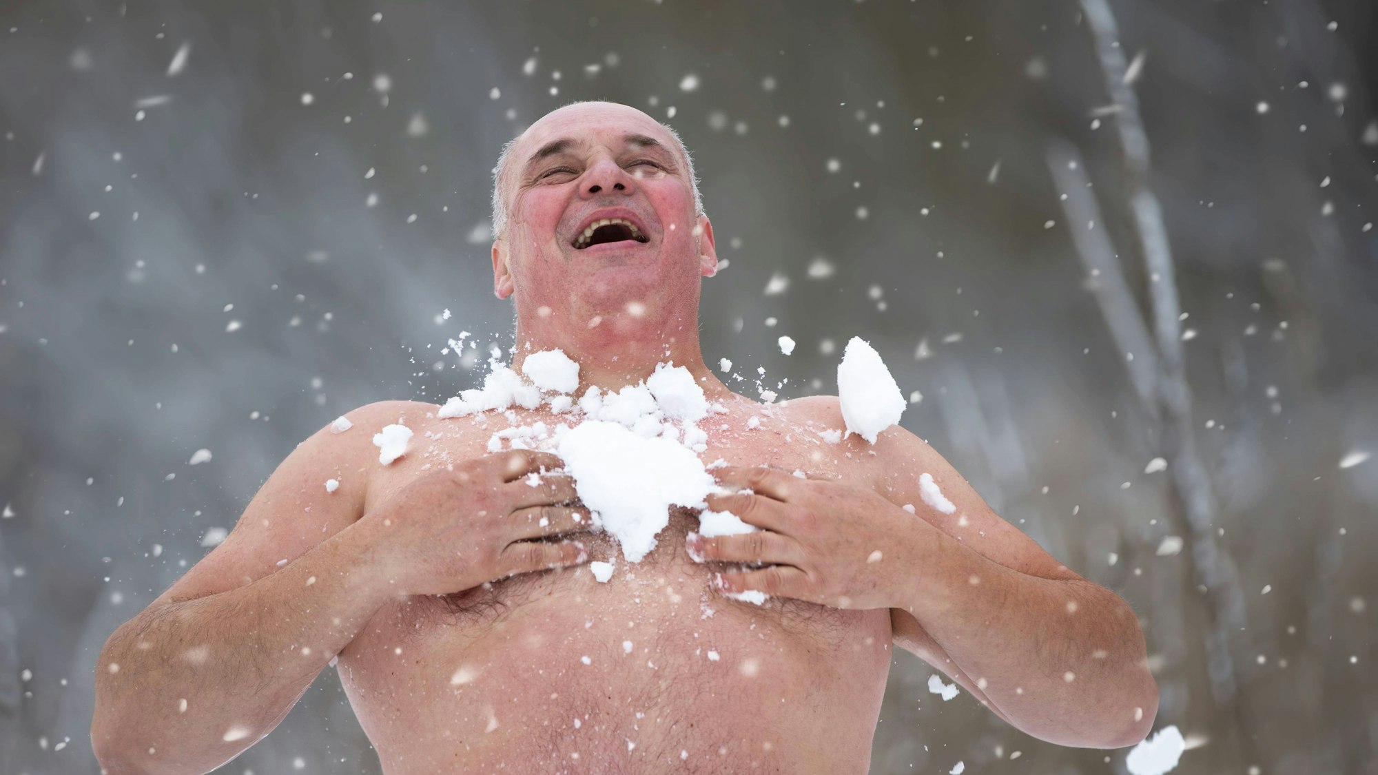 Lachender Mann beim Abhärten mit Schnee im Winter