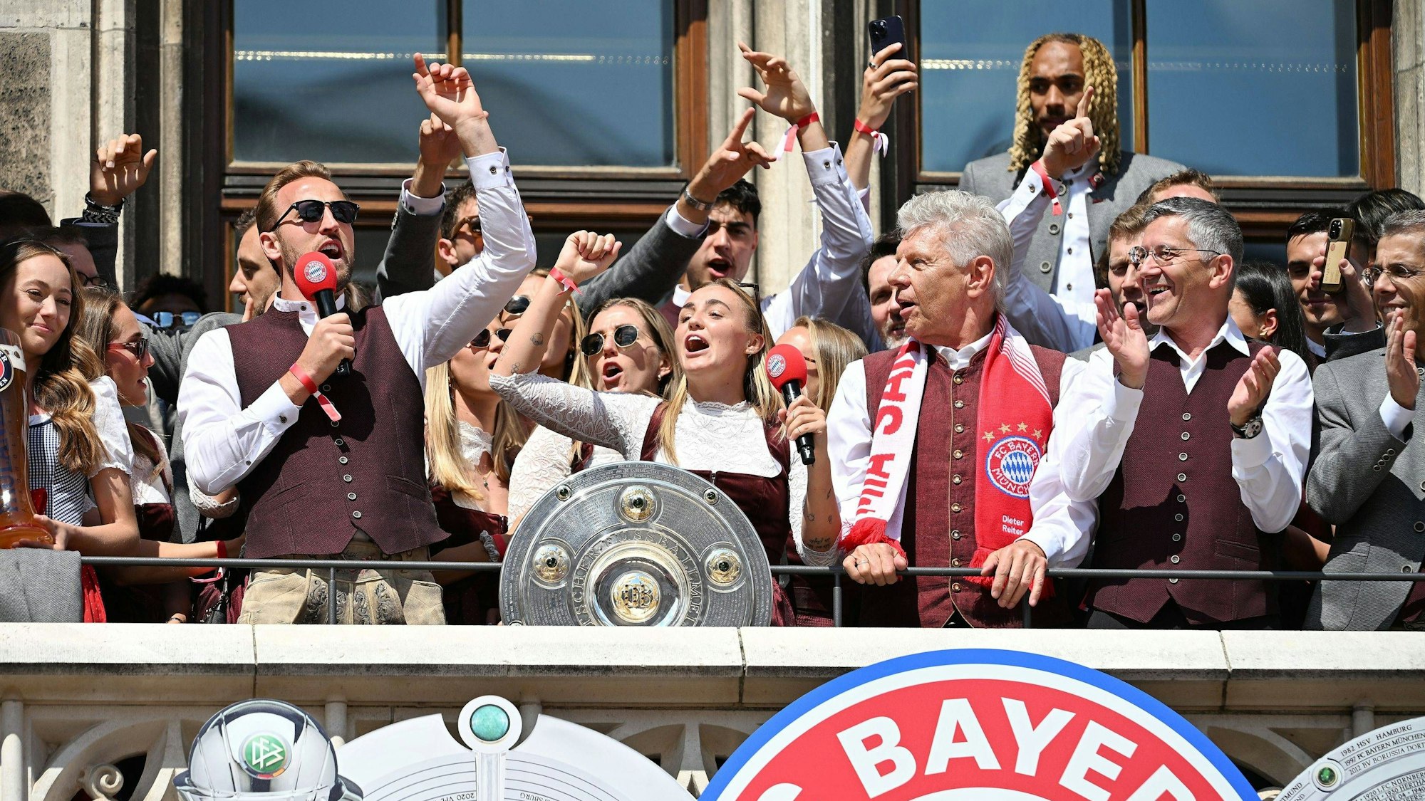 Georgia Stanway und Harry Kane singen gemeinsam auf dem Rathausbalkon in München mit der Meisterschale.