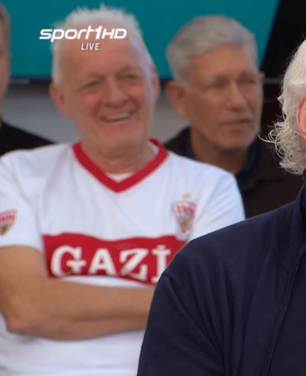 Rudi Völler sitzt mit Rollkragen-Pullover im „Doppelpass“.