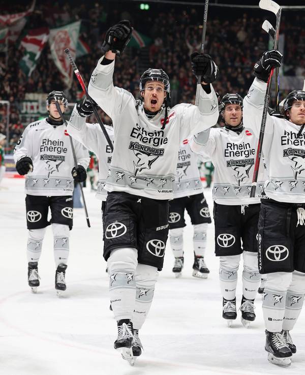 Die Spieler der Kölner Haie reißen die Arme nach oben und feiern mit den Fans.