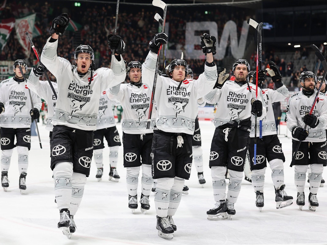 Die Spieler der Kölner Haie reißen die Arme nach oben und feiern mit den Fans.