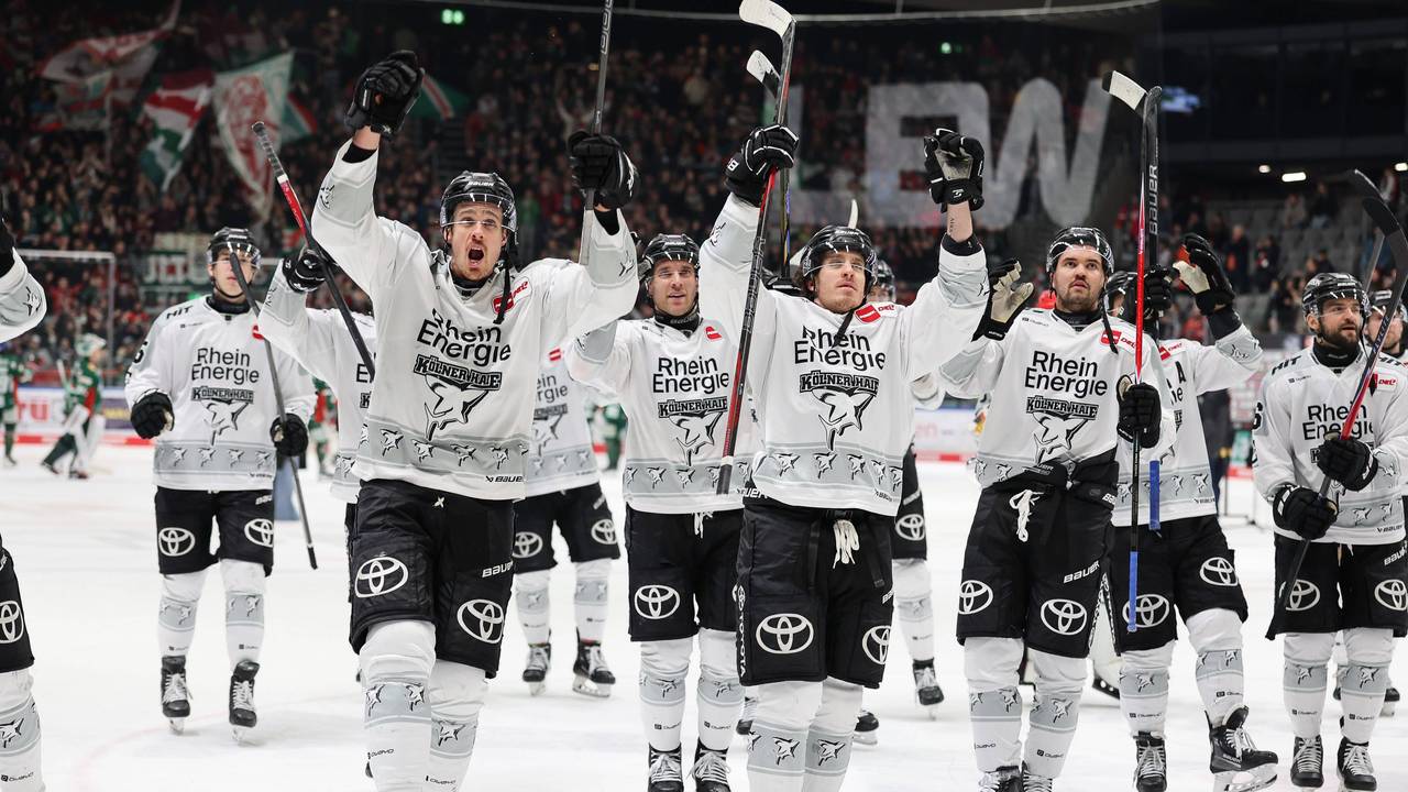 Die Spieler der Kölner Haie reißen die Arme nach oben und feiern mit den Fans.