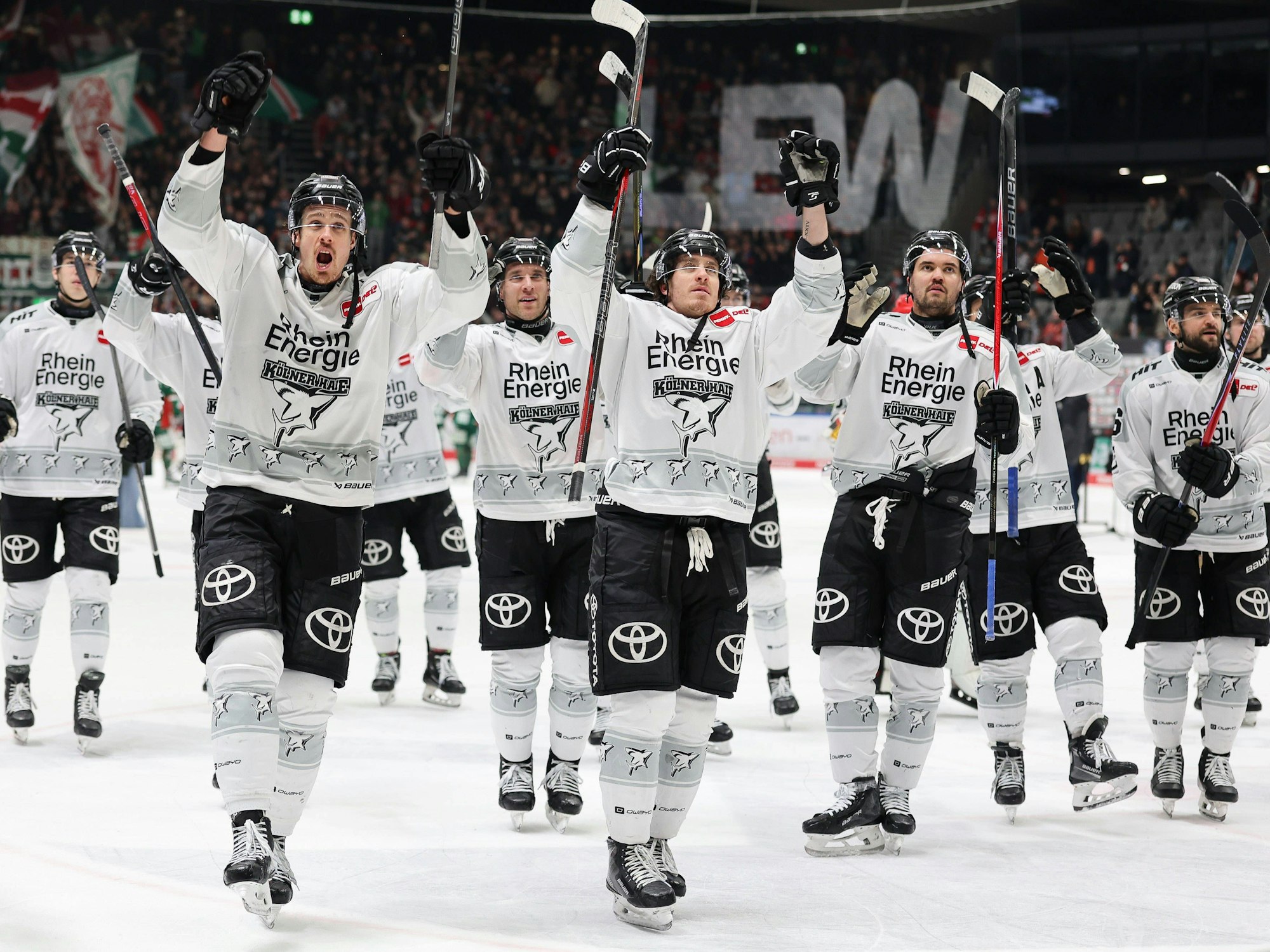Die Spieler der Kölner Haie reißen die Arme nach oben und feiern mit den Fans.
