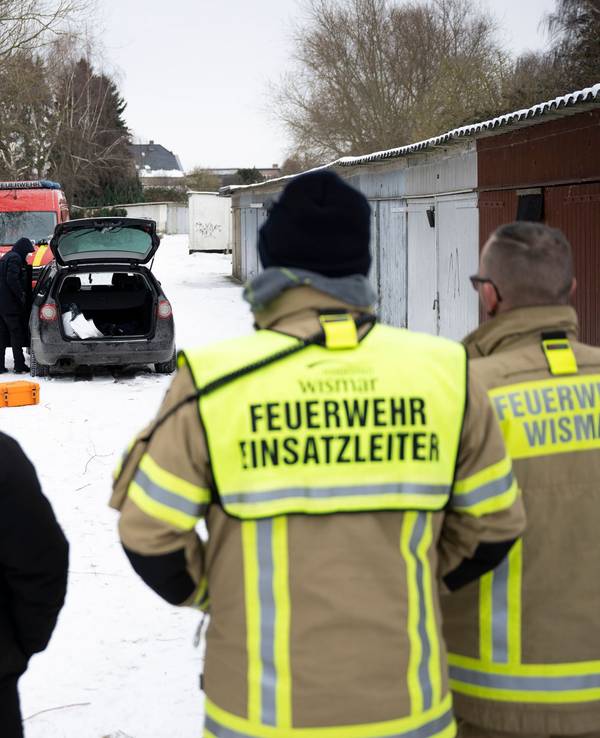 Einsatzkräfte stehen an einem zugefrorenen Gewässer.
