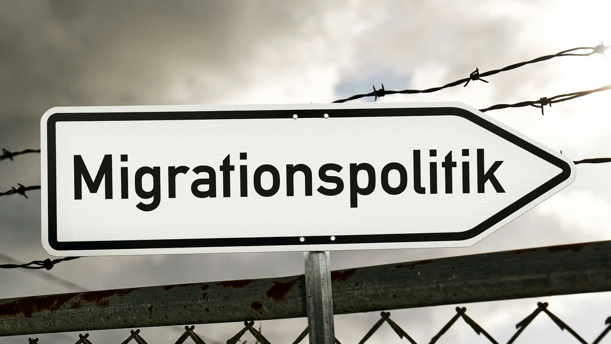 Wegweiser Migrationspolitik vor Stacheldrahtzaun