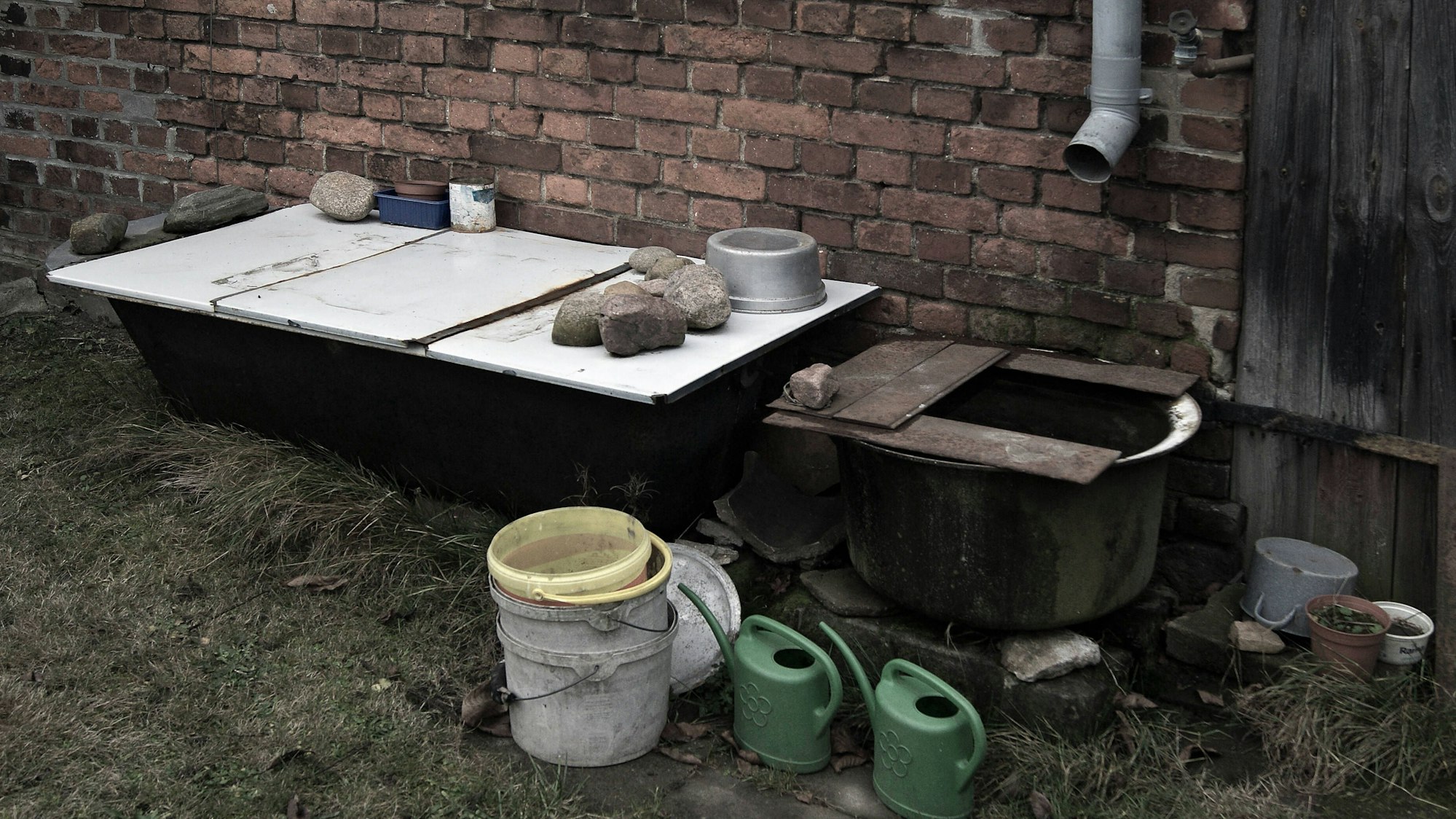 Gartenbereich mit Ziegelwand und alten Gefäßen