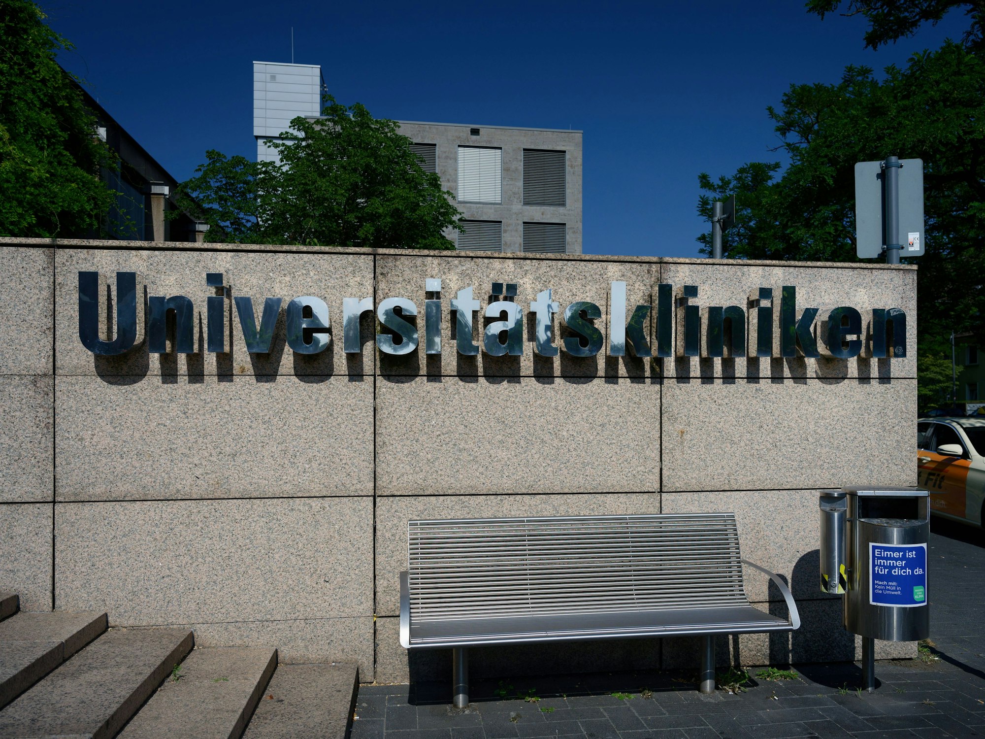 Schriftzug auf einer Steinmauer am Haupteingang des Universitätsklinikums in Köln.