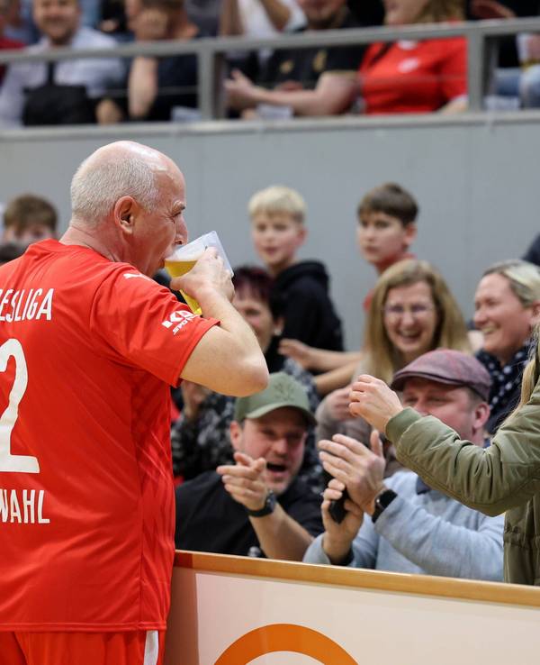 Mario Basler nimmt am Spielfeldrand einen Schluck aus einem Bierglas.
