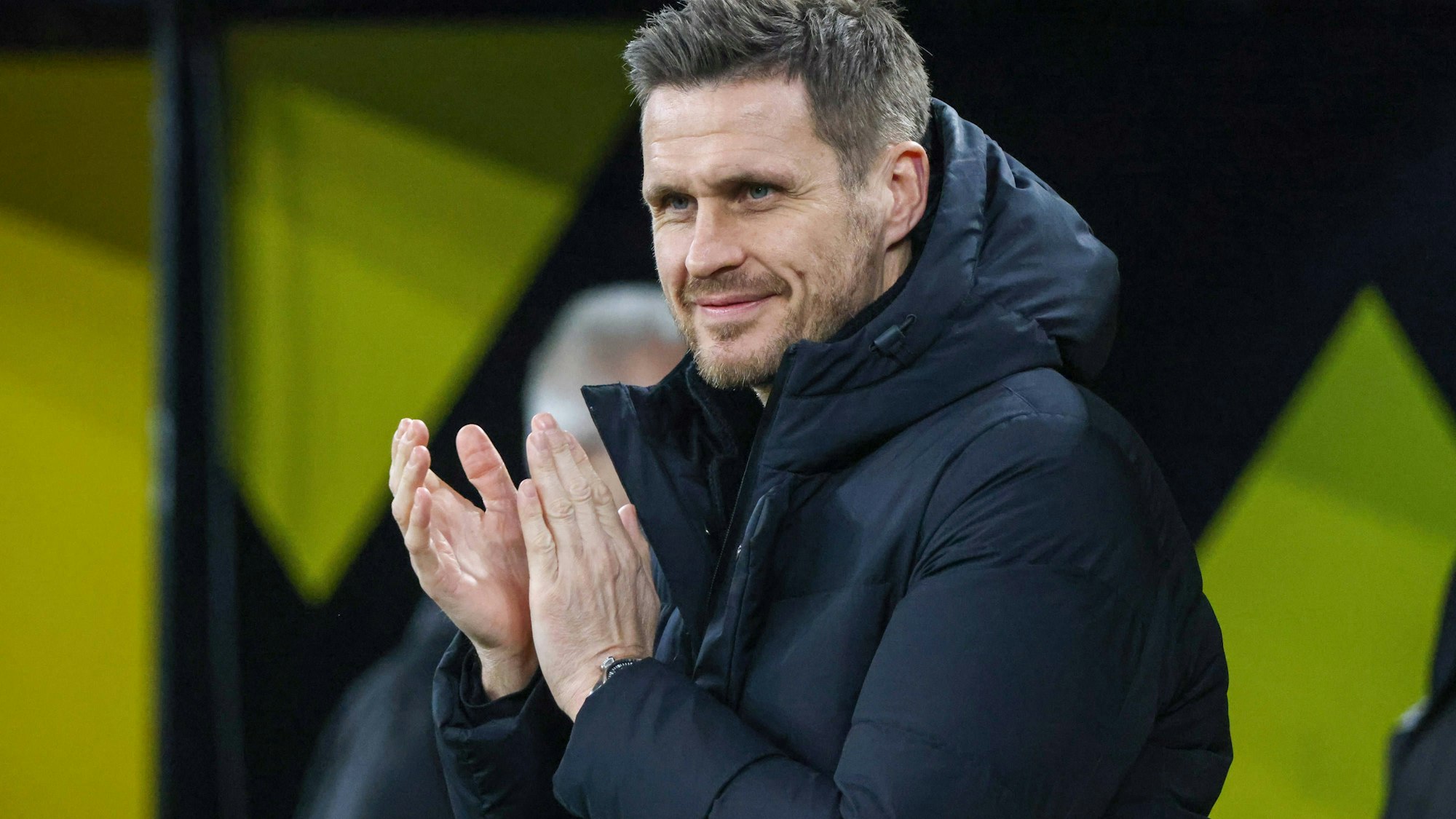 Sebastian Kehl klatscht und lächelt in dunkler Jacke.