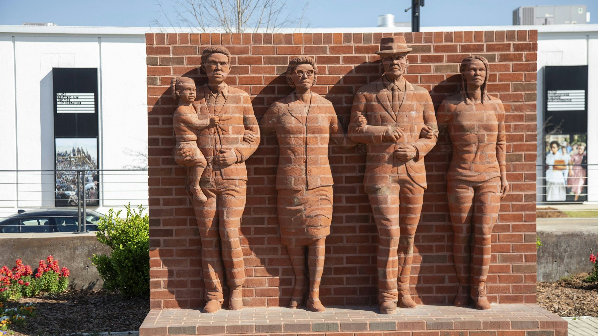 Skulpturen von Personen an einer Backsteinwand