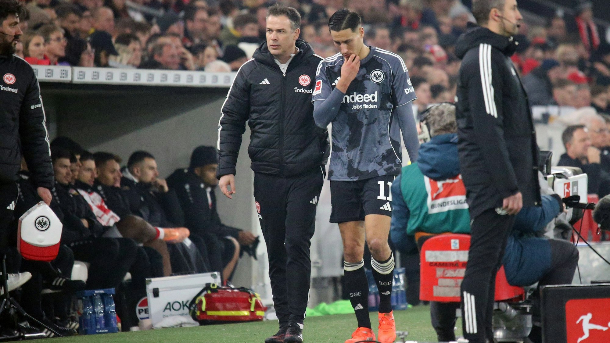 Younes Ebnoutalib wird verletzt von einem Betreuer vom Platz geführt.