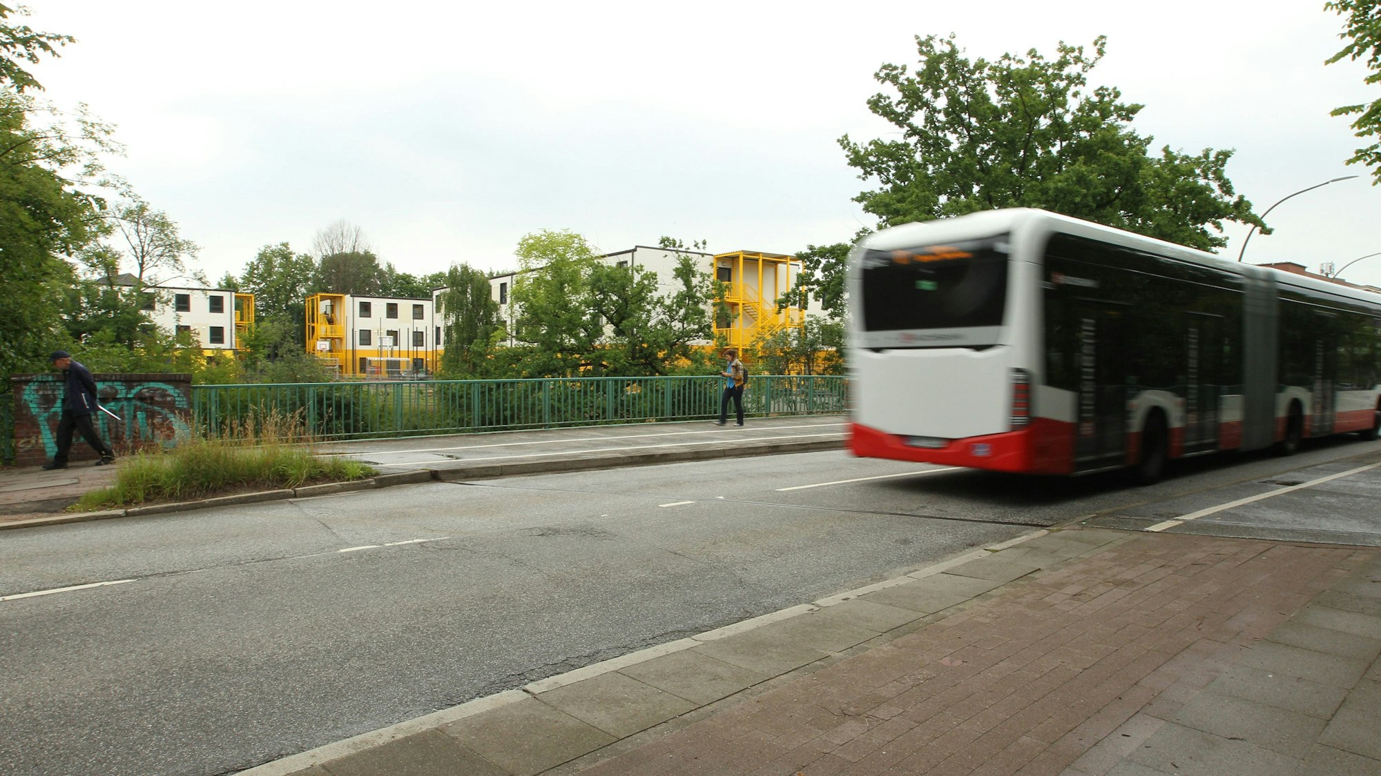 Bus fährt auf Straße, Menschen gehen vorbei
