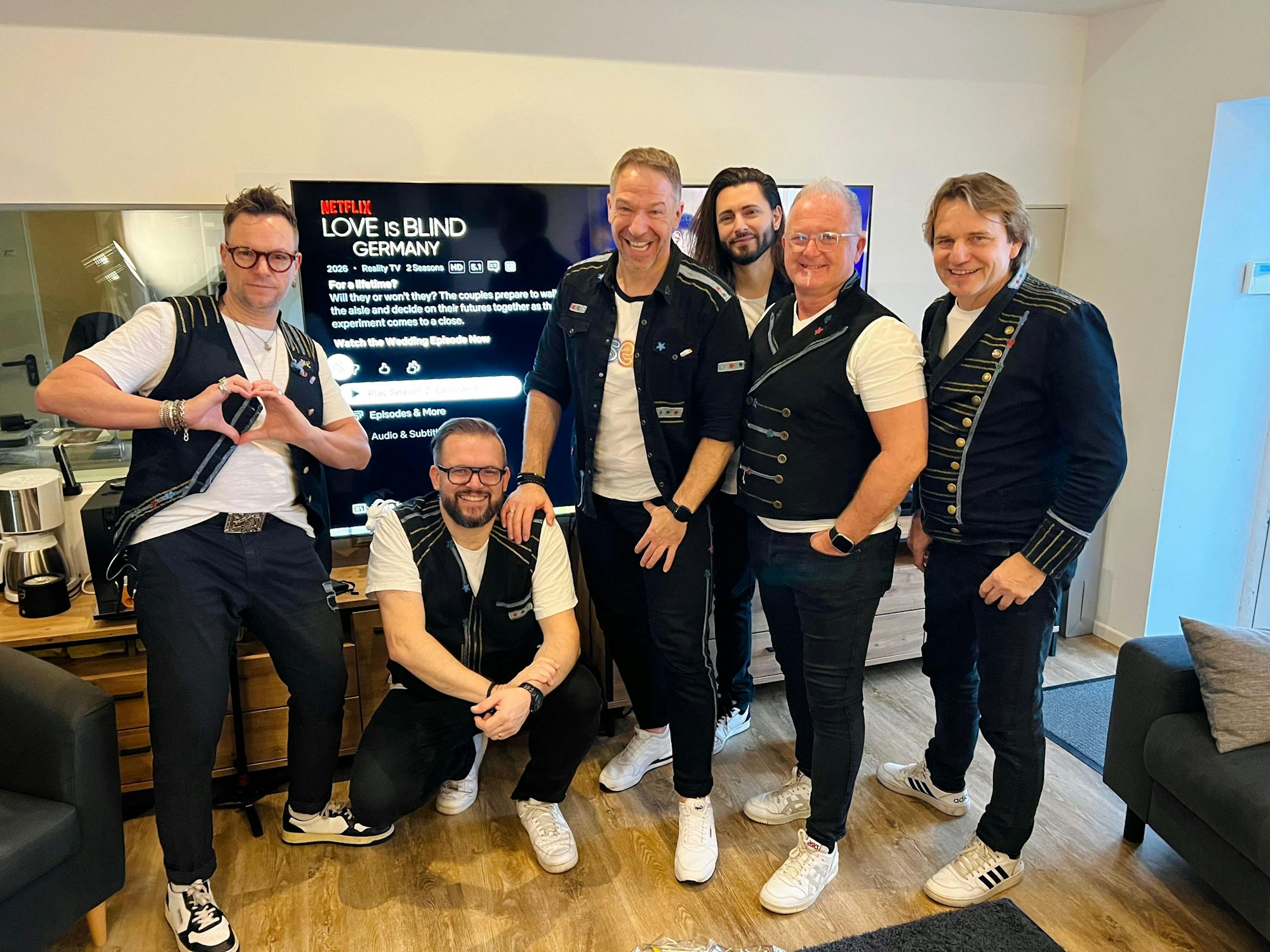 Die Höhner stehen in ihrem Büro vor dem Fernseher.
