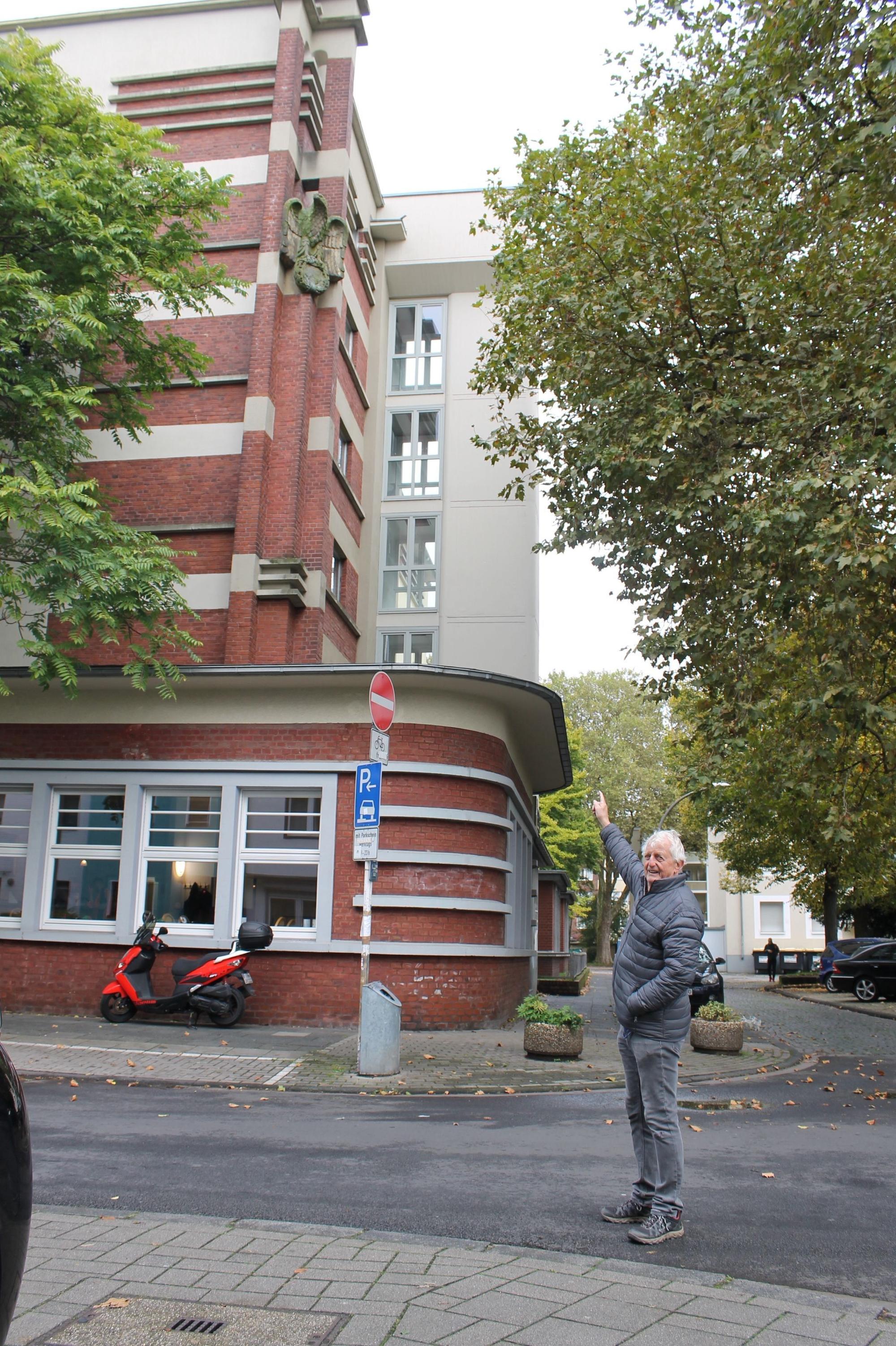 Mann zeigt auf Adlerskulptur an Kölner Gebäude