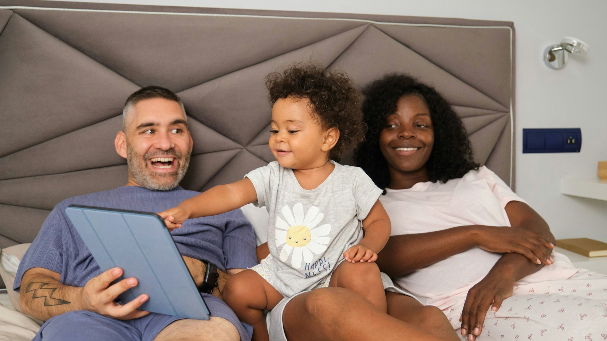 Familie spielt mit Kleinkind und Tablet