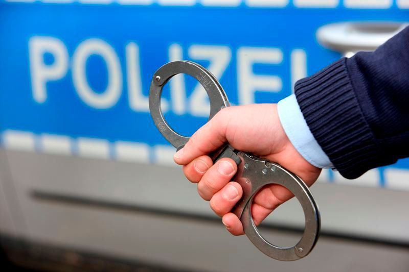 Ein Polizist hält Handschellen ins Bild.