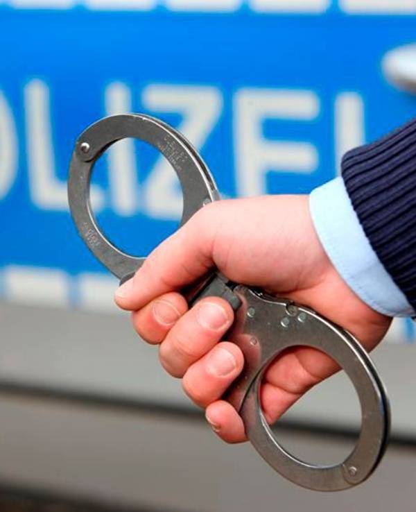 Ein Polizist hält Handschellen ins Bild.
