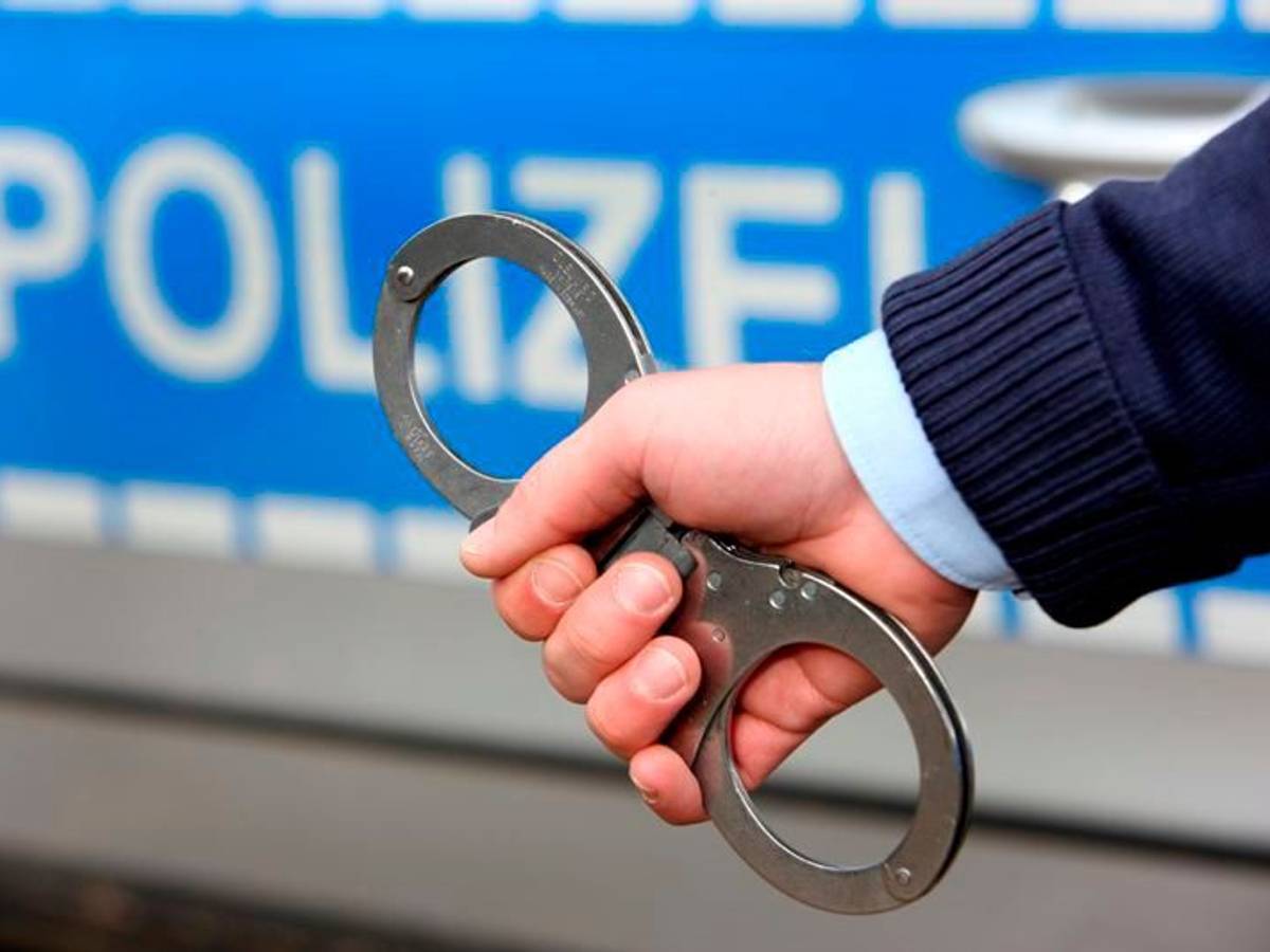 Ein Polizist hält Handschellen ins Bild.