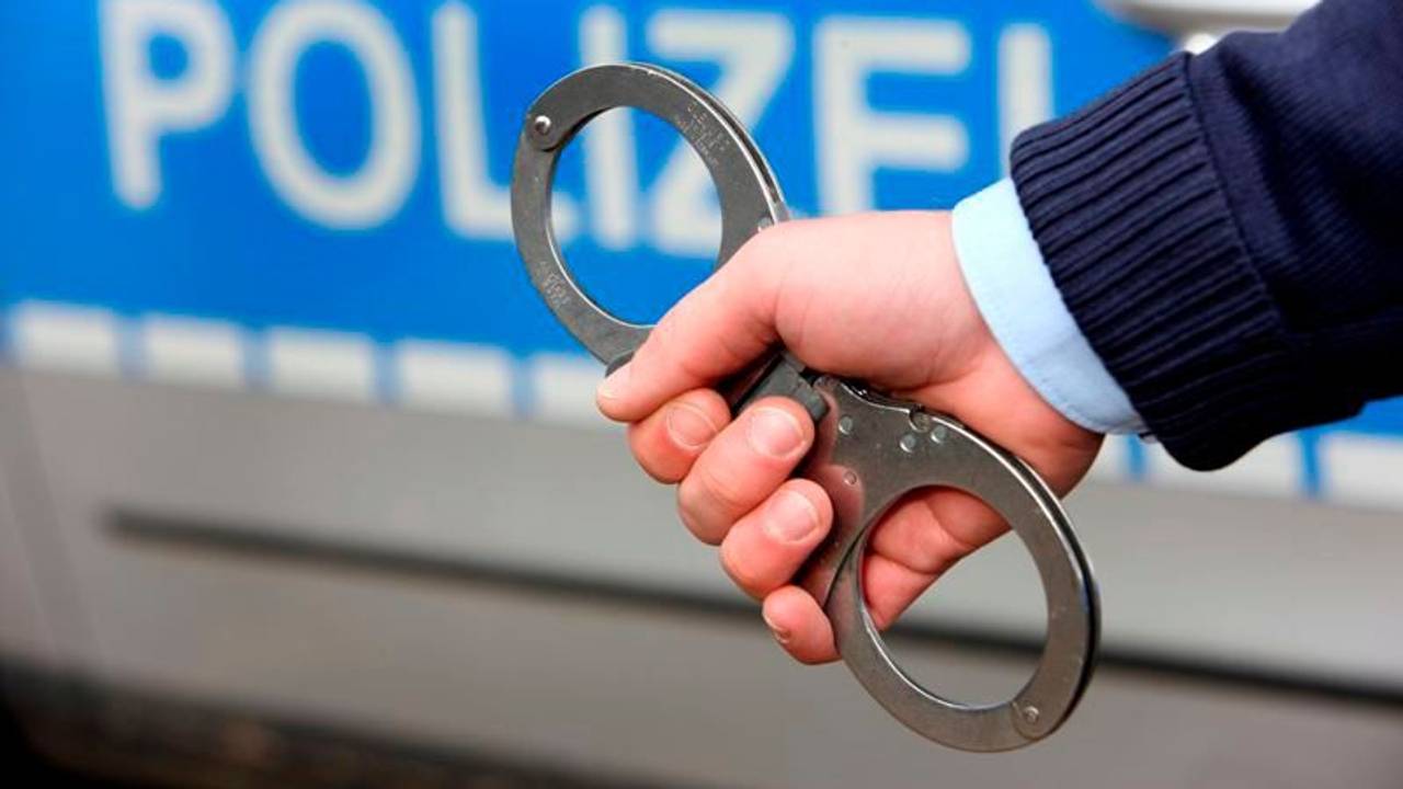 Ein Polizist hält Handschellen ins Bild.