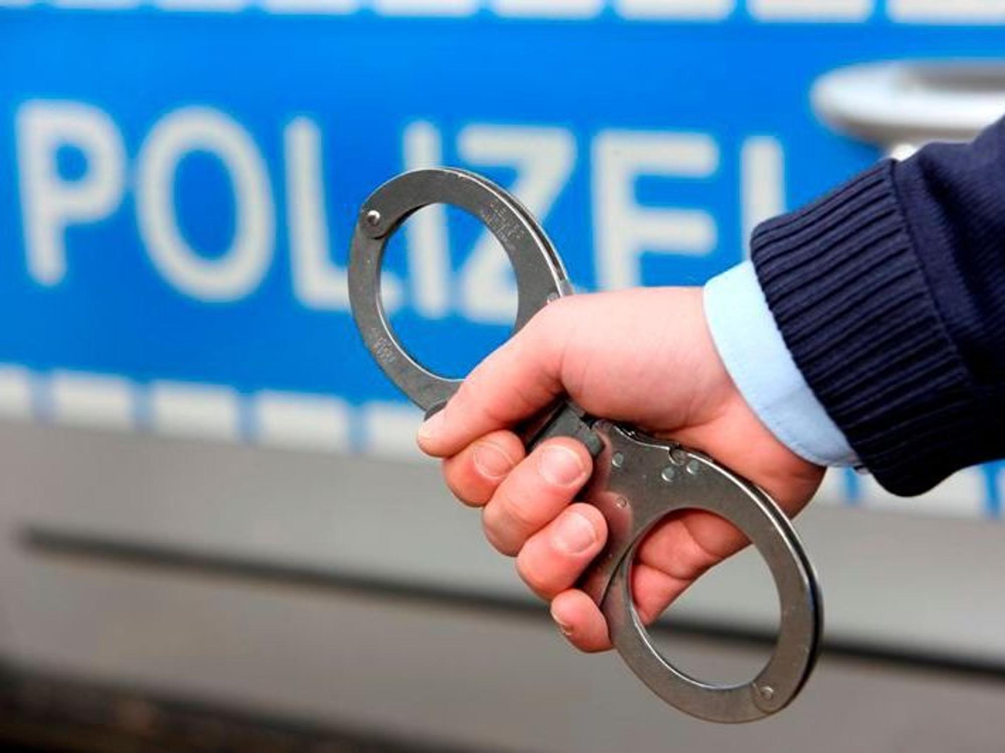 Ein Polizist hält Handschellen ins Bild.