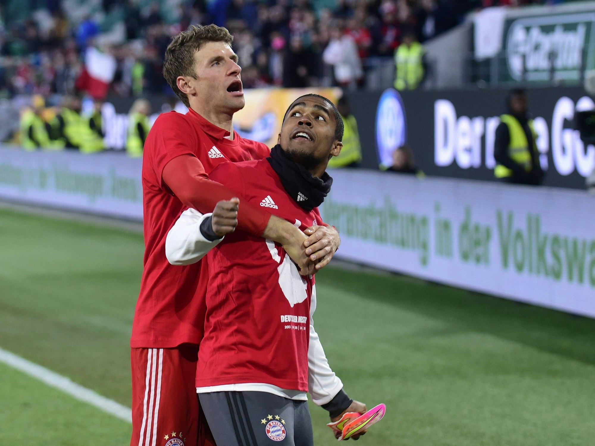 Thomas Müller umarmt Douglas Costa von hinten.