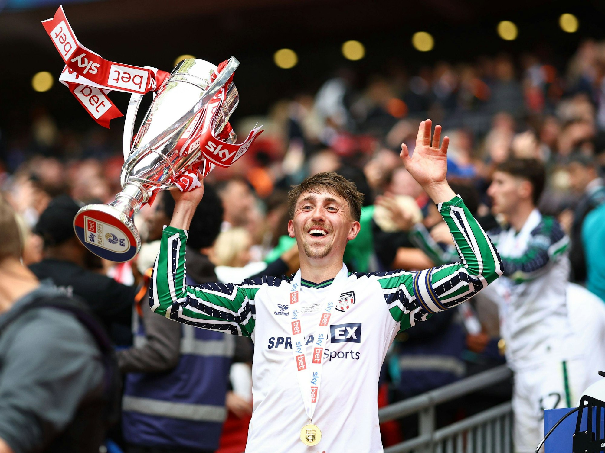 Dan Neil jubelt nach dem Aufstieg mit Pokal.