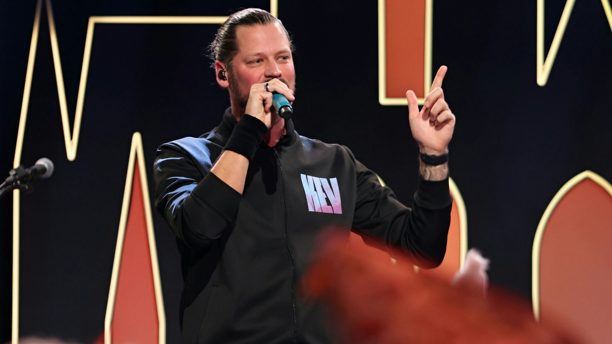 Sänger KEV steht beim Auftritt auf der Bühne.