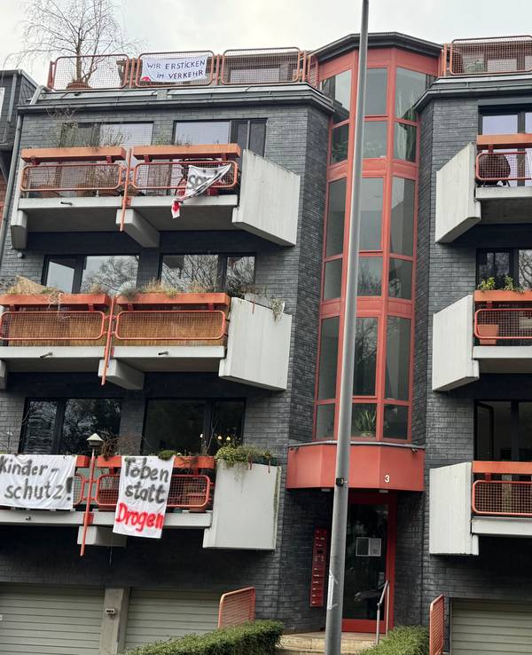 An Balkonen hängen Laken mit Aufschriften wie „Kinder brauchen Schutz“.