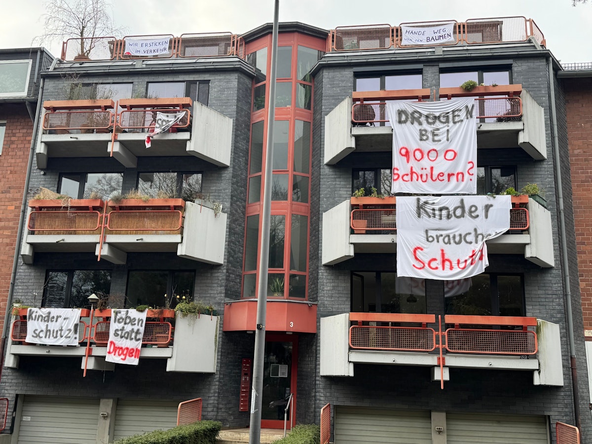 An Balkonen hängen Laken mit Aufschriften wie „Kinder brauchen Schutz“.