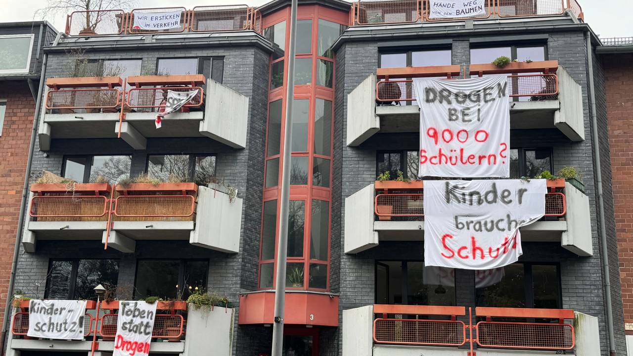 An Balkonen hängen Laken mit Aufschriften wie „Kinder brauchen Schutz“.