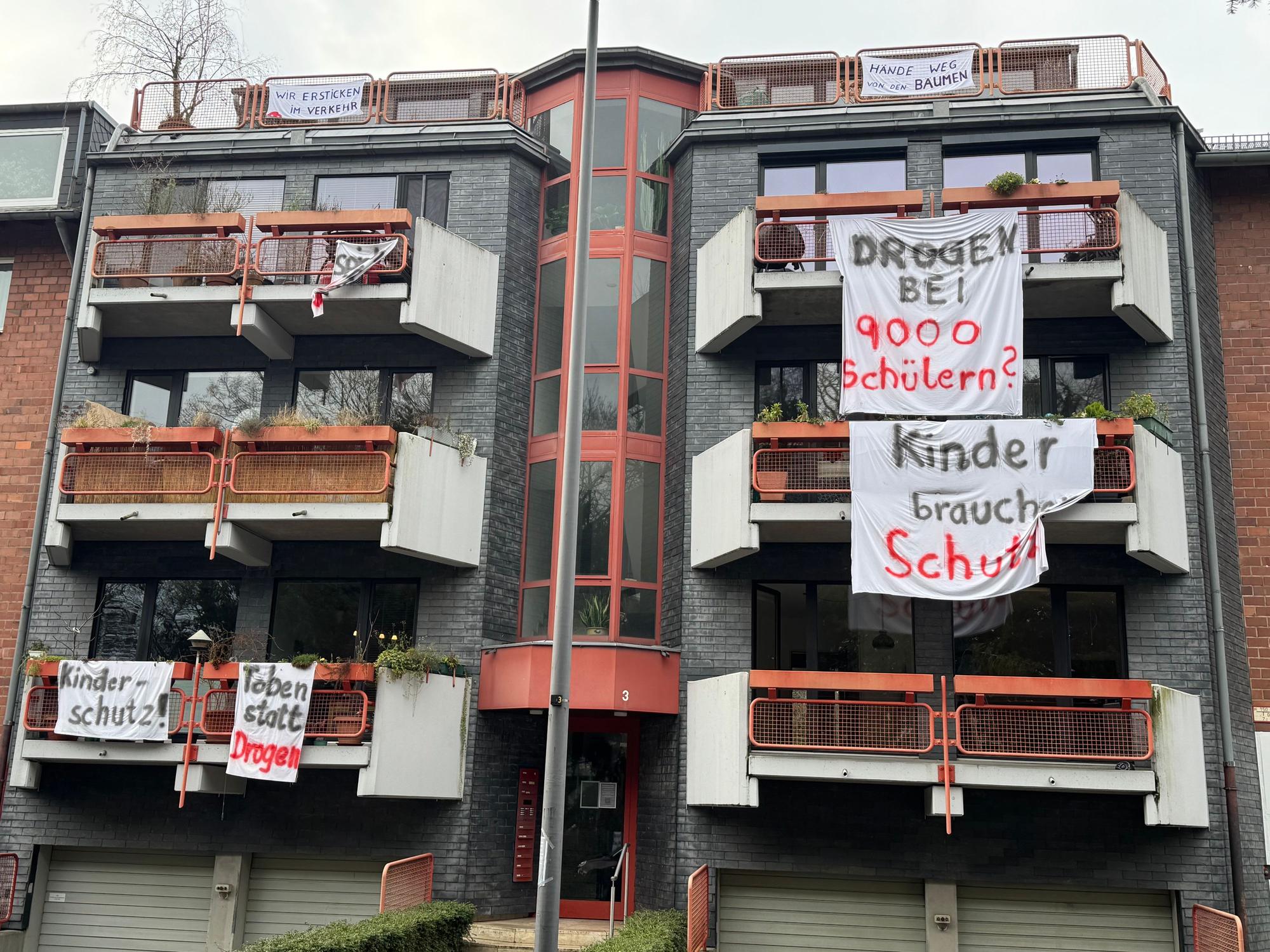 An Balkonen hängen Laken mit Aufschriften wie „Kinder brauchen Schutz“.