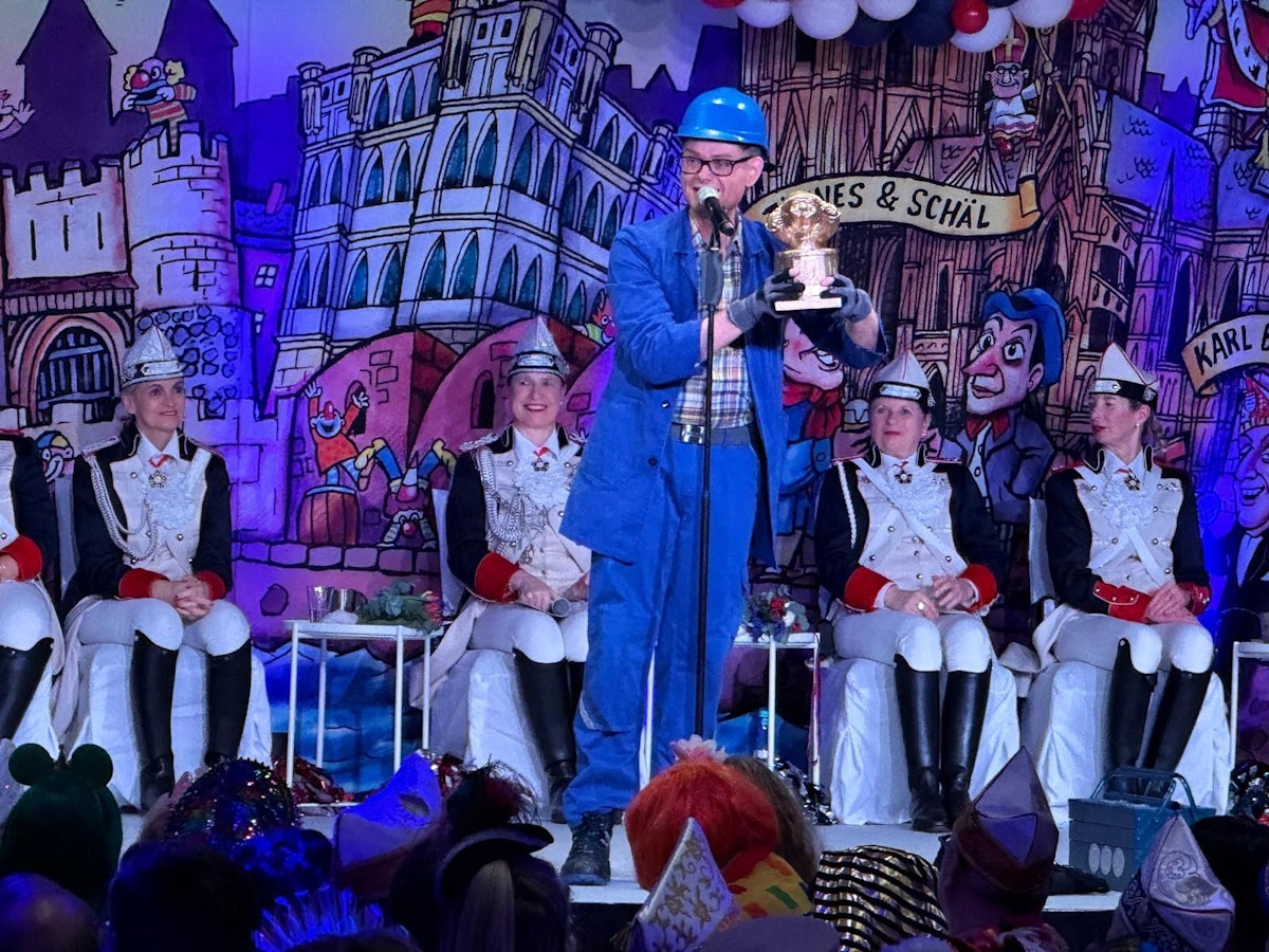 Handwerker Peters steht mit Trophäe auf der Bühne.