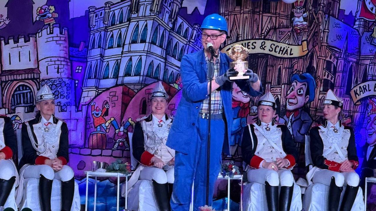 Handwerker Peters steht mit Trophäe auf der Bühne.