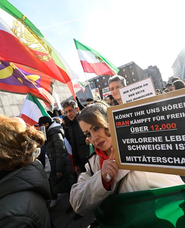 Teilnehmer halten bei einer Demonstration Schilder und Fahnen zur Unterstützung der Proteste im Iran.