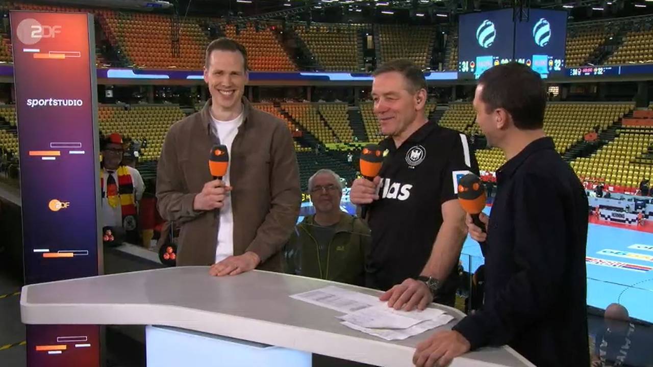 Alfred Gislason steht zwischen Moderater Florian Zschiedrich und Experte Sven-Sören Christophersen. Allre grinsen.