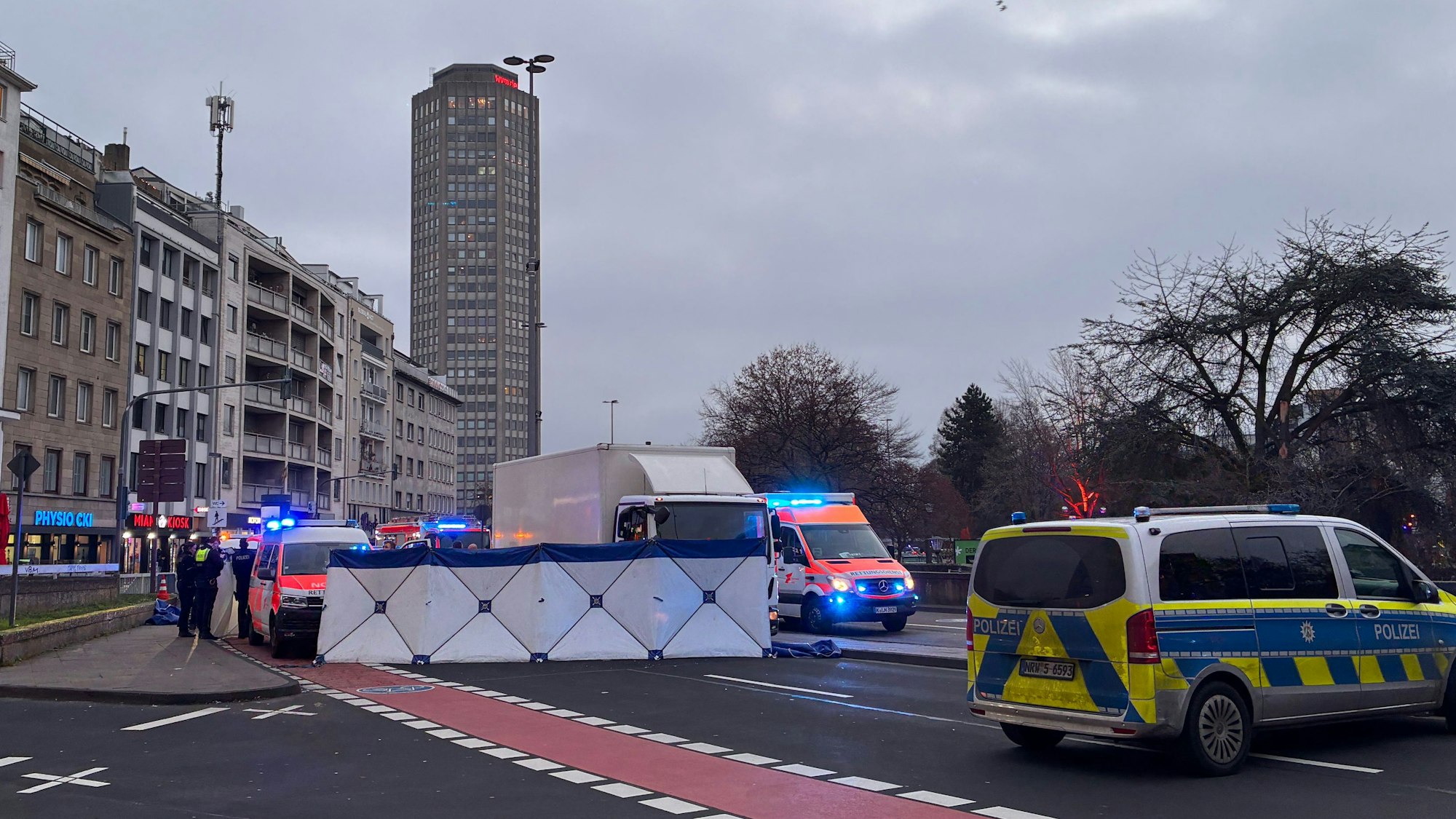 Einsatzfahrzeuge von Polizei und Rettungsdienst stehen an einem Unfallort. Dort ist ein Sichtschutz errichtet worden.